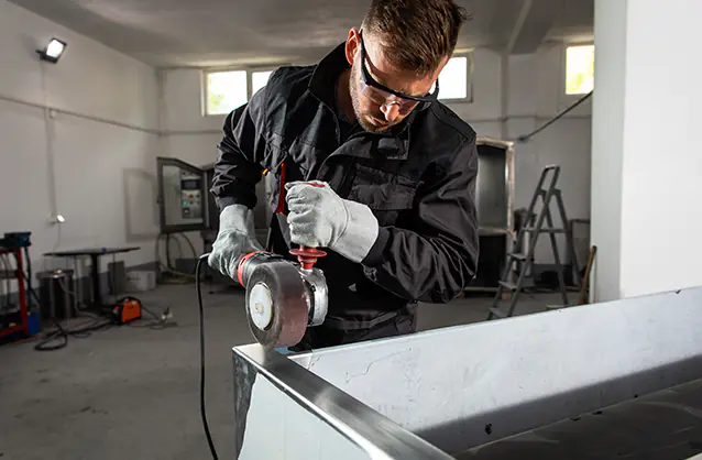 Industrial worker with angle grinder working and polishing stain