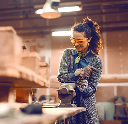 woman using a clamp with protective glasses and gloves on.