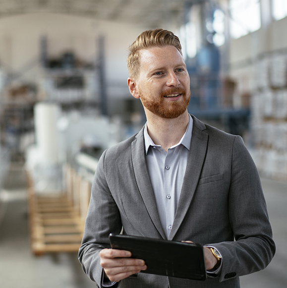 a man conducting a safety check with a clipboard in a busy factory