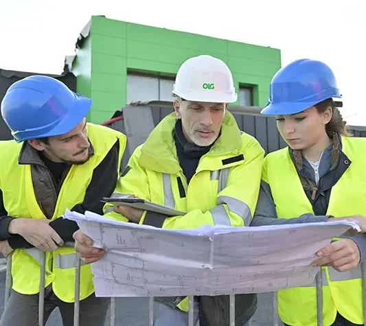 three engineers stood looking at plans outside a green building design engineering