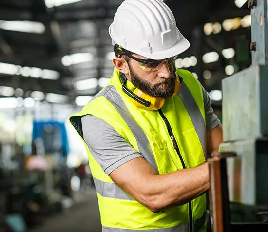 man working on machinery wearing high-vis and helmet as well as other safety gear engineering consulting